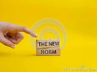 The new norm symbol. Concept words The new norm on wooden blocks. Beautiful yellow background. Businessman hand. Business and The Stock Photo