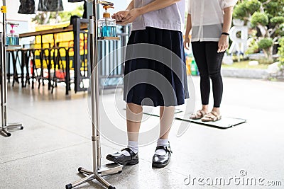 New normal,Asian student is using their foot to press the alcohol antiseptic gel,foot pedal on alcohol gel equipment,reduce touch, Stock Photo