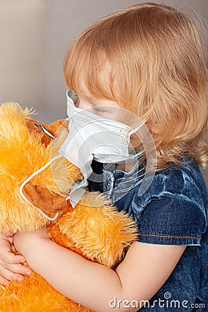 new normal family, baby Toddler blue denim dress medical mask, kissing a stuffed toy monkey Stock Photo