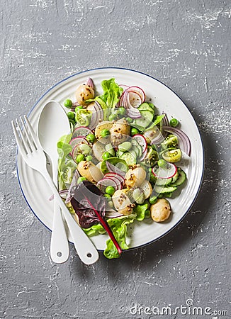 New potatoes, beans, radishes, green peas, cucumber salad with lemon mustard dressing on a gray background, top view. Healthy vege Stock Photo