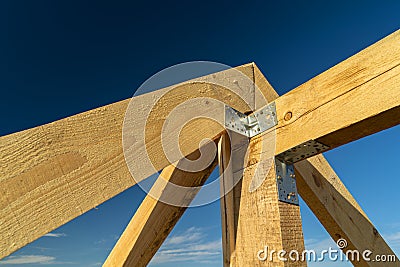 New residential construction home framing and installation of wooden beams at the roof truss system of the house against a blue Stock Photo