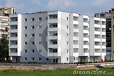 New six storey apartment building surrounded with freshly planted cypress trees and green grass Stock Photo