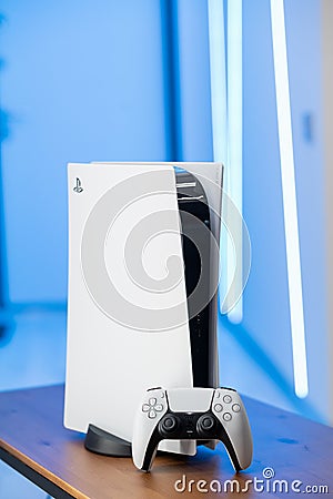 The new Sony gaming console PlayStation 5 and the DualSense controller in a blue neon color light. Moscow - November 28 Editorial Stock Photo