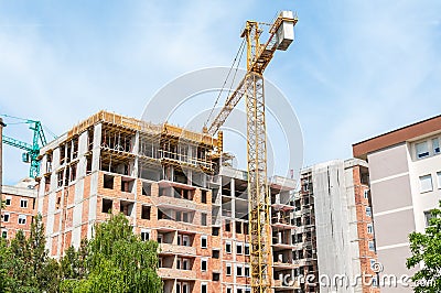 New tall residential building construction site in the city with cranes and scaffolding, blue sky background Stock Photo