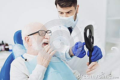 Pleasant senior man estimating dentists work Stock Photo