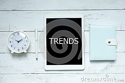 New trends technology business concept. Top view of clock,pen,notebook and tablet written with Trends on white wooden background. Stock Photo