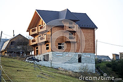 New wooden ecological traditional cottage house of natural lumber materials with shingle roof and stone basement under Editorial Stock Photo