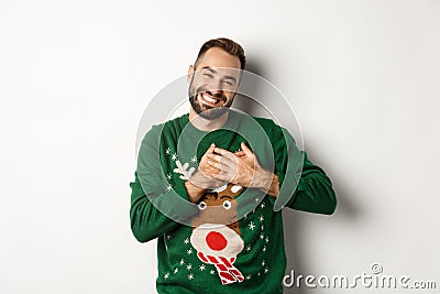 New year celebration and winter holidays concept. Happy young man looking grateful, holding hands on heart and thanking Stock Photo