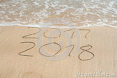 New Year 2018 is coming concept - inscription 2017 and 2018 on a beach sand, the wave is almost covering the digits 2017 Stock Photo