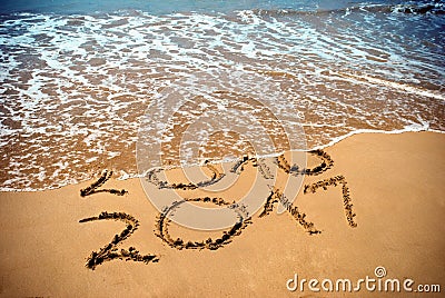 New Year 2017 is coming concept - inscription 2017 and 2016 on a beach sand, the wave is covering digits 2016. New Year 2017 celeb Stock Photo