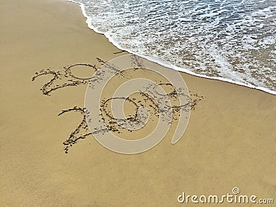 New Year 2018 is coming concept - inscription 2017 and 2018 on a beach sand, the wave is almost covering the digits 7 Stock Photo