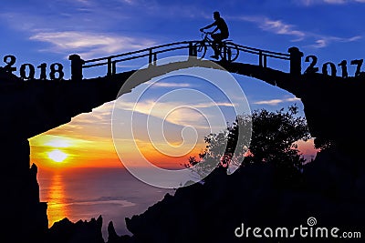 New year 2018 concept. Silhouette man and bicycle on the bridge. Stock Photo