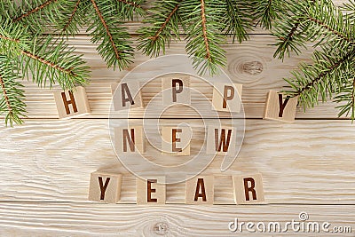 New year greetings happy new year, creative the inscription on the cubes. Wooden background with branches of blue spruce. Stock Photo