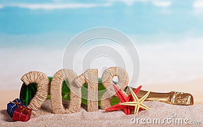 New Year inscription 2018, bottle of champagne, gifts and starfish in the sand on beach. Stock Photo