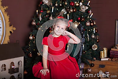 New Year 2020! Merry Christmas, happy holidays! Portrait of a little girl in a red dress and with bows on her head sits on a chair Stock Photo