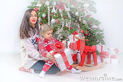 New Year photo session. Young woman and baby girl with gift near Christmas tree Stock Photo