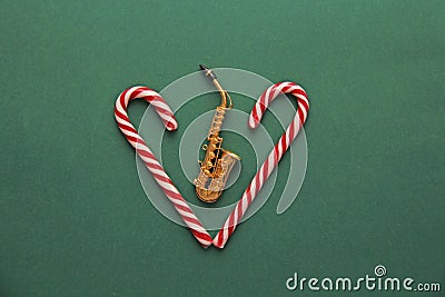 New Year`s card - golden saxophone and candy cane. Green backgro Stock Photo