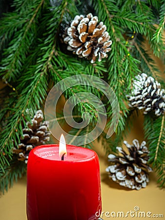 New Year's decorations. Pine cone, candle and fir branches on a beige background. Stock Photo