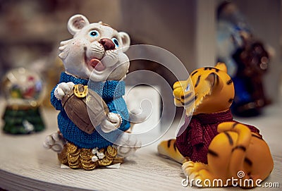 New Year`s toys. Figurine white lion cub piggy bank with a barrel of money in his hands in a blue sweater and a figurine of a red Stock Photo