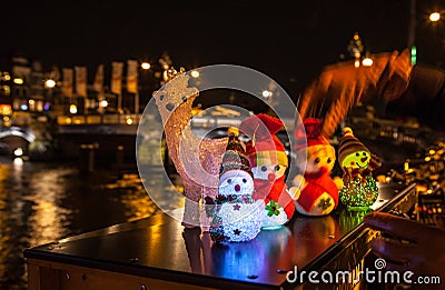 New Year`s toys snowmen and deer pose against night canals of Amsterdam. Stock Photo
