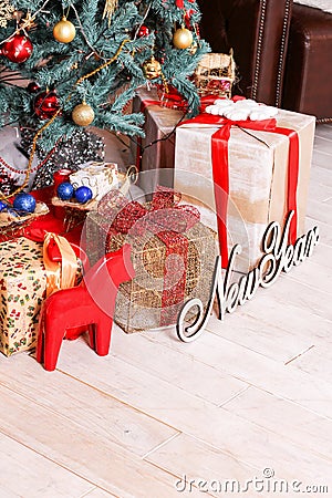 The New Year`s tree decorated with spheres and a garland, gifts, the inscription `New Year` and a red figurine of a horse Stock Photo