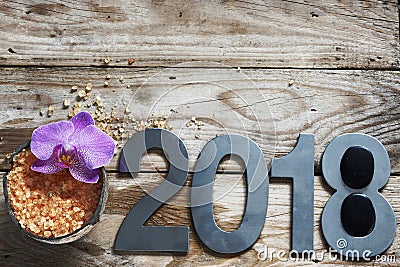 New Year 2018, spa set on wooden table, coconut and bath salt, flower of orchids and stones for hot massage Stock Photo