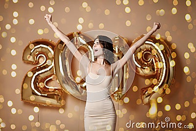 Portrait Of Beautiful Smiling Girl In Shiny Golden Dress Throwing Confetti, Having Fun With Gold 2019 Balloons On Background. Stock Photo