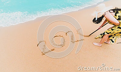 2020 New Year. 2020 woman written on sandy beach with wave foam at sea beach. Happy New Year. Tropical celebration.New Years Stock Photo