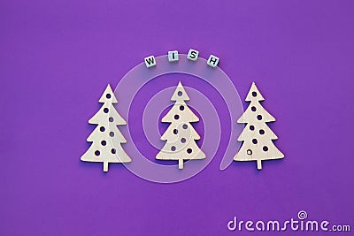 New Year wooden ornaments, top view. Wooden Christmas tree. Violet background. Flat lay style. Inscription wish. Stock Photo