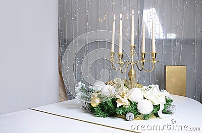 New Year& x27;s decorations and a golden candlestick with burning candles stand on the surface of a white grand piano Stock Photo