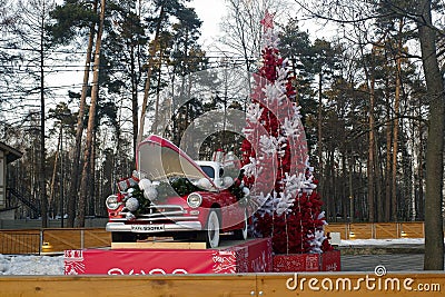 New Year's decorations in Pekhorka park. Artificial red pine tree and red old timer GAZ-M20 Pobeda delivering gifts. Editorial Stock Photo