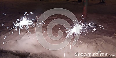 A New Year's fireworks display is lit, standing in the snow. Sparklers Stock Photo