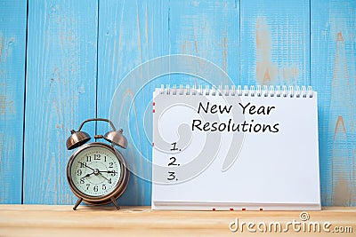 New years Resolutions text on notebook and retro alarm clock on table and copy space. Goals, Mission and New Start Stock Photo