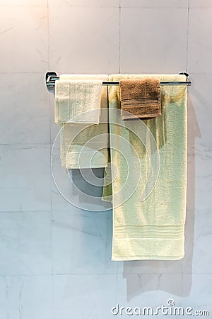 New yellow and brown folded towels hanging on metal rail under l Stock Photo