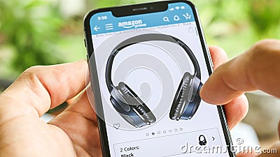 Man searching Headphones on Amazon app with Mobile Smart iPhone Editorial Stock Photo