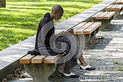 New York City, USA - June 10, 2017: African american woman using her mobile phone in a public park during coffee break Editorial Stock Photo