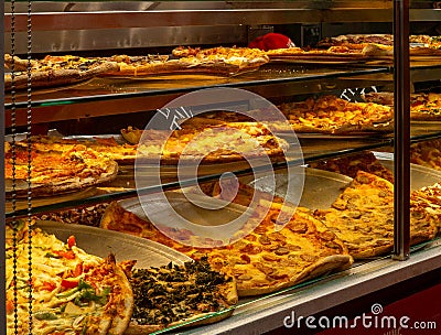 Horizontal view of traditional New York City pizzeriaâ€™s display case with a variety of pizza Editorial Stock Photo