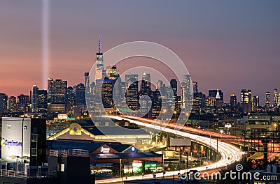 The 9/11 tribute lights seen next to One World Trade at sunset. Car light trails from Interstate 278 I-278 heading towards Manha Editorial Stock Photo