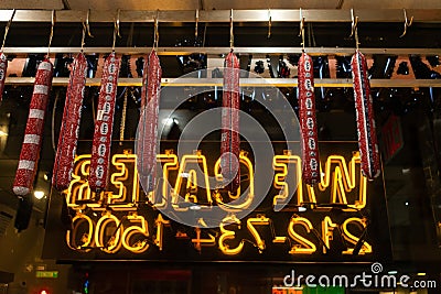 Pastrami hanging from ceiling in front of neon writing Editorial Stock Photo