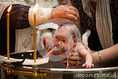 Newborn baby baptism in Holy water. baby holding mother`s hands. Infant bathe in water. Baptism in the font Stock Photo