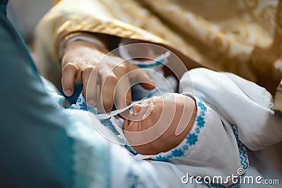 Newborn baby baptism by oil with hands of priest Stock Photo