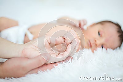 Newborn baby boy holding mom`s thumb. Mother`s hand resting in dad`s hand Stock Photo