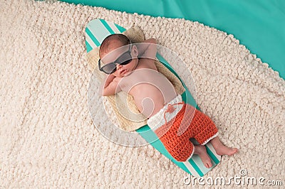 Newborn Baby Boy Sleeping on a Surfboard Stock Photo