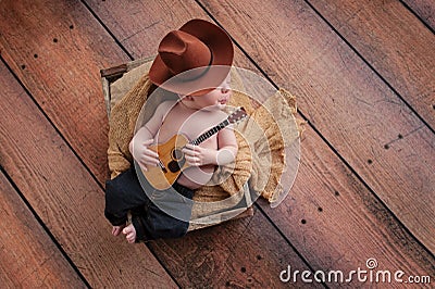 Newborn Baby Cowboy Playing a Tiny Guitar Stock Photo