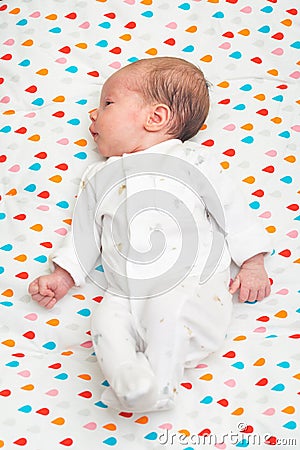 Newborn baby dressed in white sleeping on her back Stock Photo