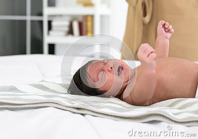 Newborn baby girl or boy crying on white bed at home Stock Photo