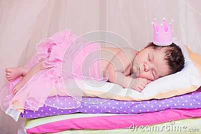 Newborn baby girl in a crown sleeping on the bed of mattresses. Fairy Princess and the Pea Stock Photo