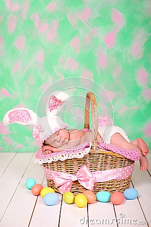 Newborn baby girl in a rabbit costume has sweet dreams on the wicker basket. Easter Holiday Stock Photo