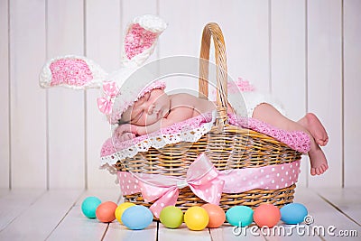 Newborn baby girl in a rabbit costume has sweet dreams on the wicker basket. Easter Holiday Stock Photo