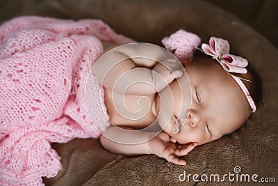 Newborn baby girl sleeping cute, covered with soft pink scarf, neatly folded under a pen with a small head with a pink bow, set Stock Photo